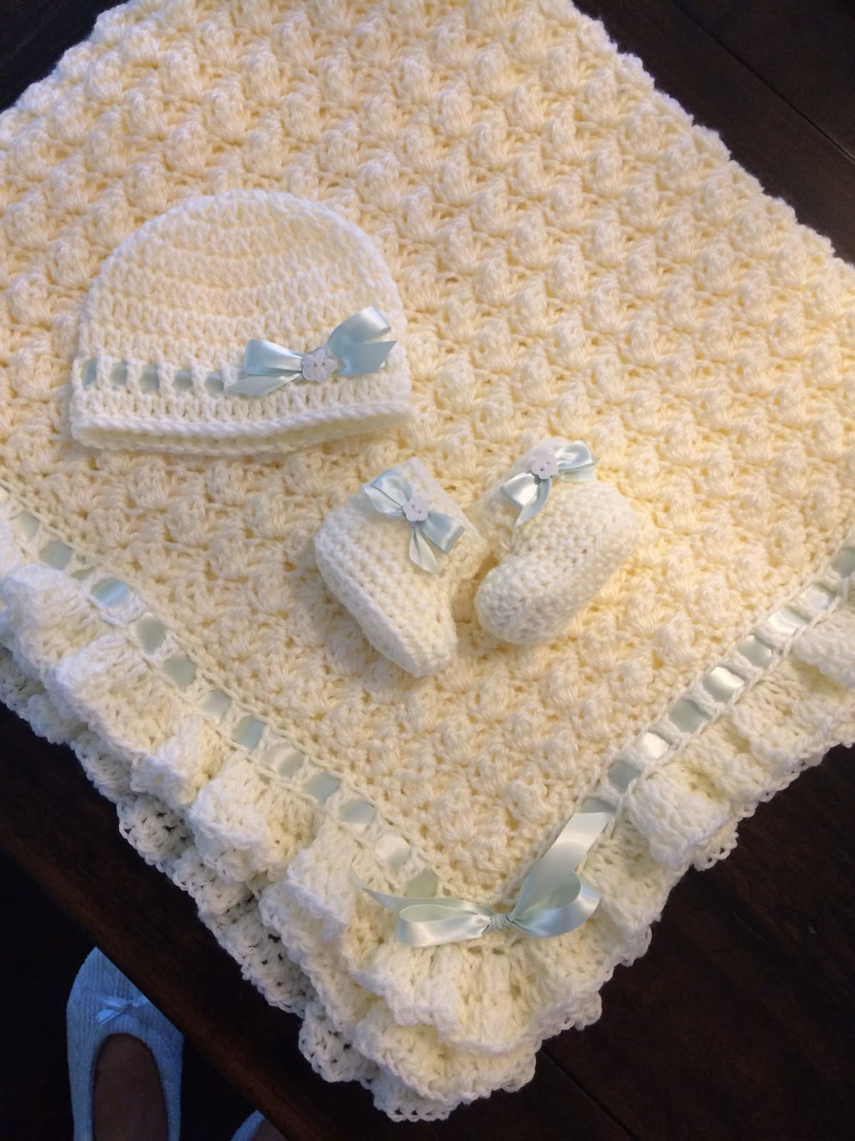 Cream crochet baby blanket with matching hat and booties and blue bows made from the tutorial