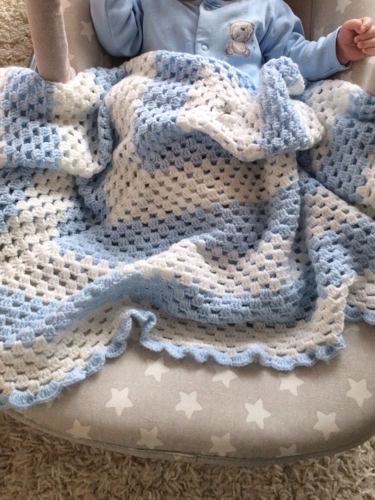 Blue and white crochet baby blanket photographed with a baby, made from the tutorial