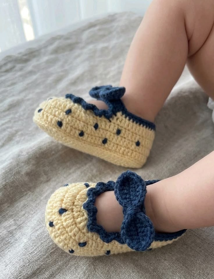 Cream crochet baby shoes with navy-blue bows made from the tutorial